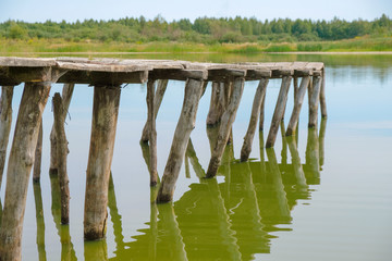 Empty old footbridge on the lake. The bridge is handicraft. Low water level in the lake in Ukraine.