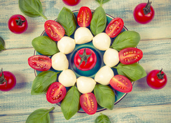 Tomato and mozzarella with basil leaves on a plate. Caprese salad.