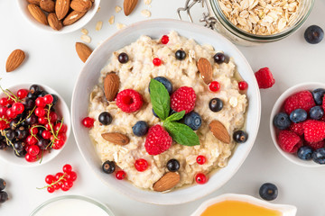 oatmeal porridge with fresh berries, nuts, honey and mint in a bowl for healthy diet breakfast