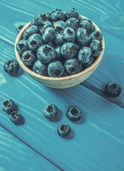 Raw fresh huckleberry in a bowl. Wooden background.