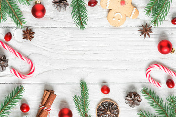 Christmas frame made of fir branches, decorations, berries, candy, christmas food and pine cones. flat lay