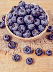 Raw fresh huckleberry in a bowl. Wooden background.