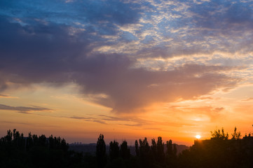 Landscape with dramatic light - beautiful golden sunset with saturated sky and clouds.