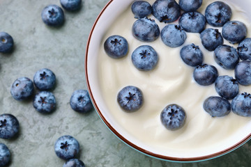Bowl with yogurt and blueberries on table, top view