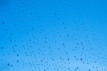 Raindrops on the surface of window glass with a blurred background.