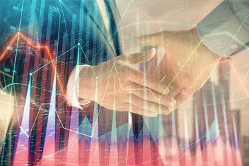 Double exposure of financial graph on cityscape background with two businessman handshake. Concept of stock market deal