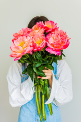 Girl covers her face with a beautiful bouquet of pink peonies, happy birthday or valentine's day
