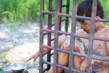 dirty boy in a cage reaches for a plate in nature, nothing is in the plate, he hangry