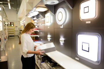 Beautiful young woman shopping chandelier lights fro her home