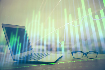 Stock market graph on background with desk and personal computer. Double exposure. Concept of financial analysis.