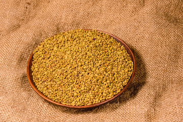 Ceramic plate with fenugreek seeds on a sackcloth