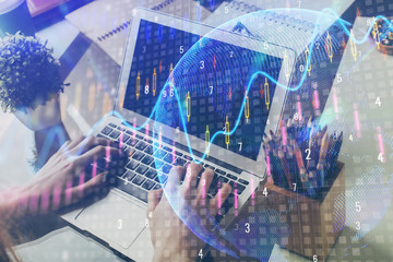 Double exposure of graph with man typing on computer in office on background. Concept of hard work.