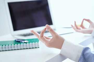 Calm businesswoman meditating at work, focus on female hands in mudra, close up view. Peaceful mindful employee practicing exercises at workplace.