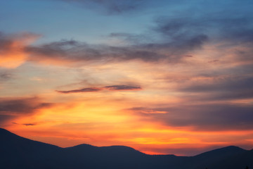 Fototapeta premium Background of bright sky at sunset. Mountain silhouettes.