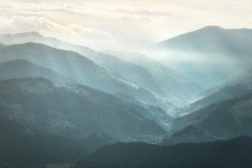 Mountain landscape. View of Carpathian mountain range with visible silhouettes through the colorful fog.