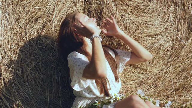 Woman in straw hat with flowers against haystack
