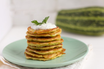 fresh delicious zucchini pancakes with sour cream and herbs on the table