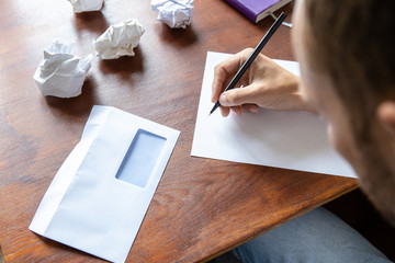 a man writes a letter on a sheet by hand