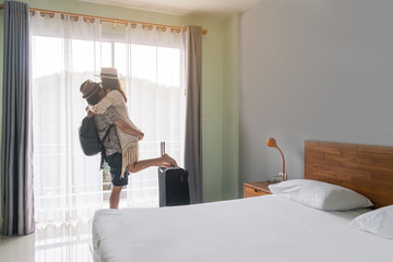 Young happy couple traveler with luggage at the hotel room on summer vacation