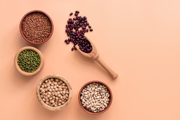 Healthy food, bowls a variety of legumes, red and white beans, chickpeas, buckwheat, mung beans on pastel pink background. Top view, place for text.