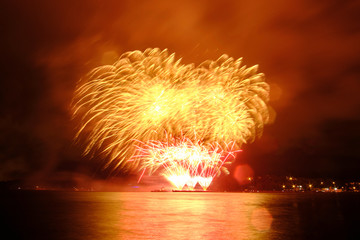 Beautiful colorful fireworks in sky over river. Big festive evening event with great pyrotechnic show.  