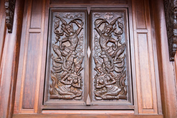 Native Thai style carving, painting on church door in the temple.