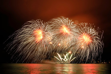 Beautiful colorful fireworks in sky over river. Big festive evening event with great pyrotechnic show.  