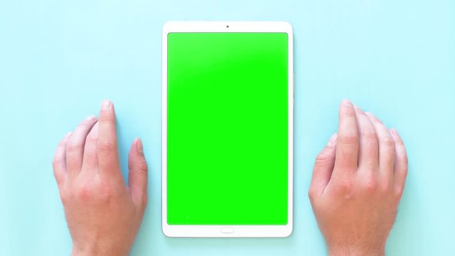Men's hands knock on the surface with a tablet. Green screen footage. 4k top view.