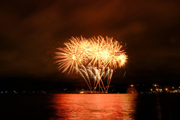Beautiful colorful fireworks in sky over river. Big festive evening event with great pyrotechnic show.  