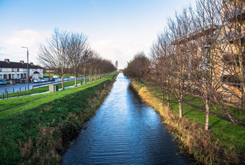 Fototapeta na wymiar Canal lined with trees and footpaths on a clear winter day. Dublin, Ireland.