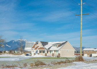 Family house with mountain view and front yard in snow on winter sunny day