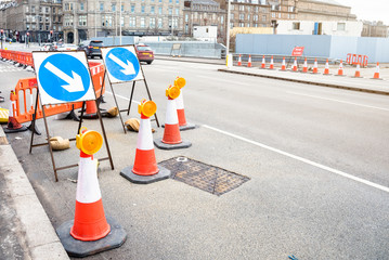 Traffic signs and cones indicating the closure of a lane of a wide street beacuse of roadworks