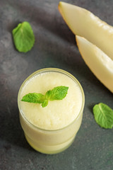 Close-up of smoothie melon in a glass with mint leaves on a dark background. Selective focus