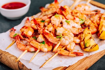 Sweet Chili Shrimp Skewers with lemon and parsley on gray stone background