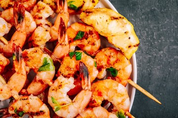 Sweet Chili Shrimp Skewers with lemon and parsley on gray stone background