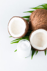 Ripe half cut coconut and cream with green leaves on a white isolated background. Healthcare and medical concept. Skin care.