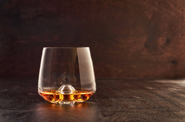 A crystal glass of whiskey on a wooden table.