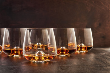 Set of six glasses of whiskey on a wooden table