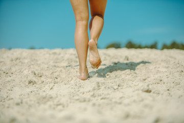 woman legs walking by sand beach summer time