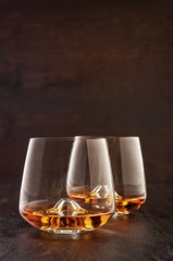 Two crystal glasses of whiskey on a wooden table.