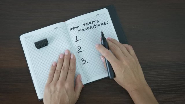 New year's resolutions. The woman writes down her goals in a notebook.