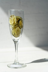 Glass goblet with dried lime slices on the white background. Side view