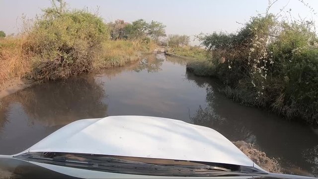 Offroad 4x4 vehicle crossing water hole in Moremi Game Reserve Botswana at Third Bridge