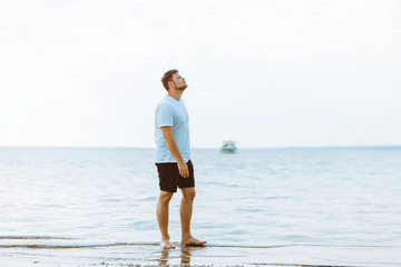 man walking barefoot by sea beach summer time