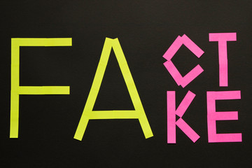 Fake News concept. The inscription FACT and FAKE on a black background.
