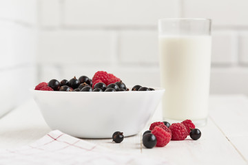 bowl with fresh berries and glass of milk