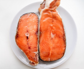 two UN-cooked red salmon fish steak on white plate on white background