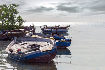 Fototapeta na wymiar floating dhow wooden hulls moored awaiting repairs and refurbishment at a traditional zanzibar harbor