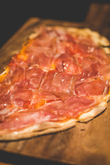 Baked Focaccia Di Recco with Parma Ham served on a wooden plate