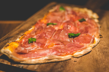 Baked Focaccia Di Recco with Parma Ham served on a wooden plate